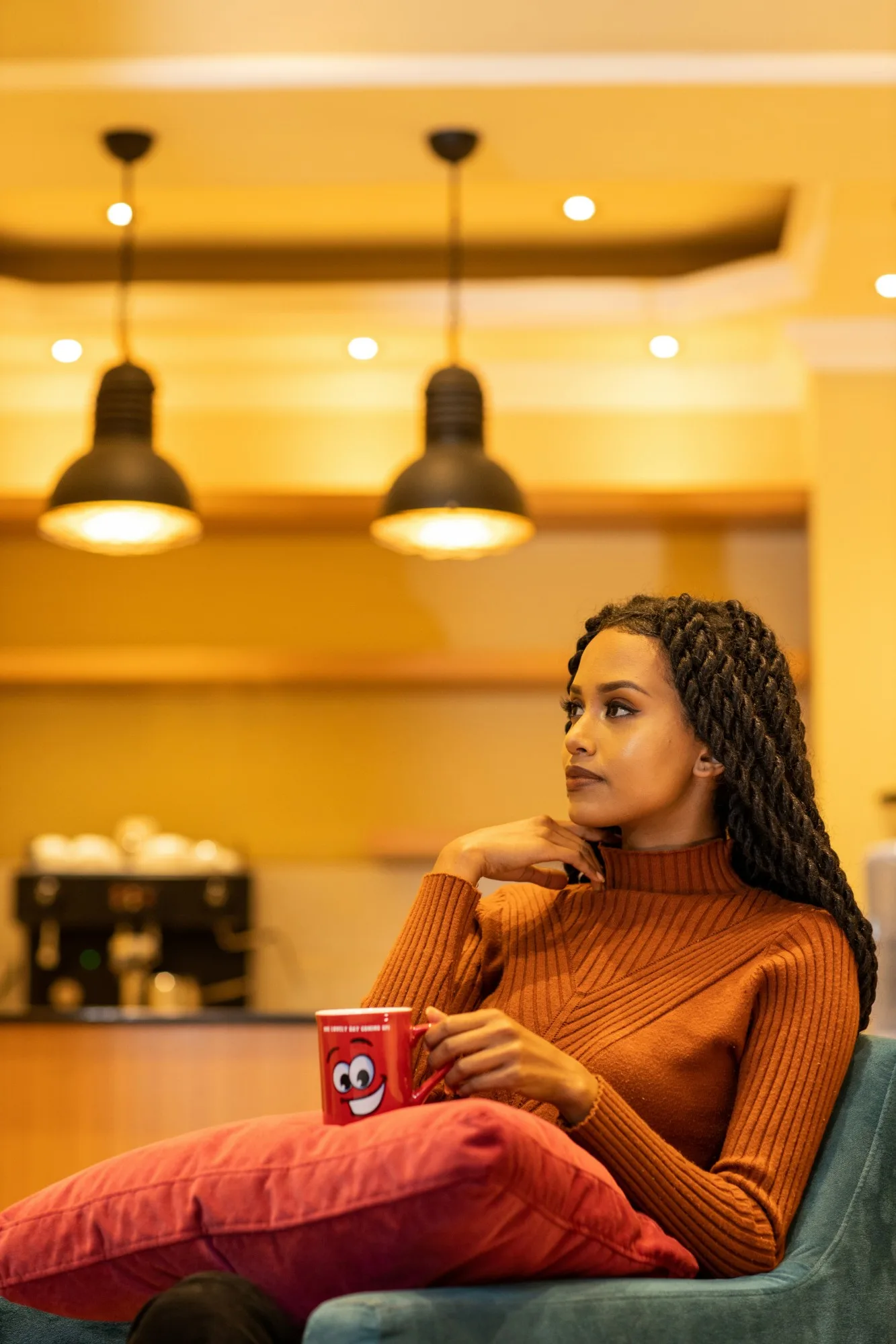 A woman holding a red mug of coffee in a warmly lit café